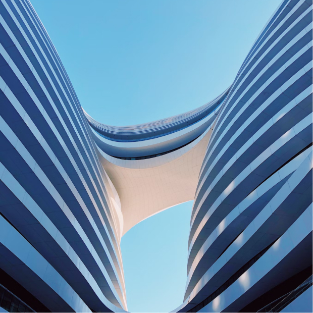 Ground level photo of two buildings with blue sky behind