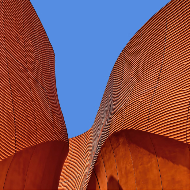 Ground level photo of two buildings with blue sky behind